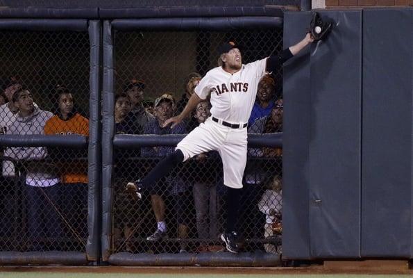 Pence slams into the fence in game 4 against the Nationals as fans look on.