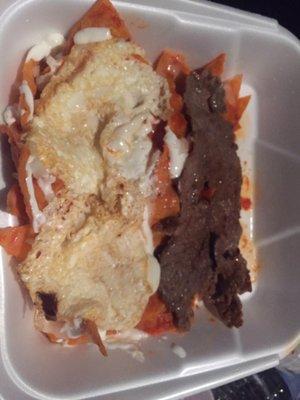 Chilaquiles Rojas with fried eggs and beef steak.