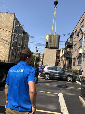 Commercial AC unit installation using a crane to get it onto the roof of the building.