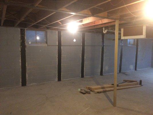 Carbon fiber support straps installed to stabilize a bowing basement wall