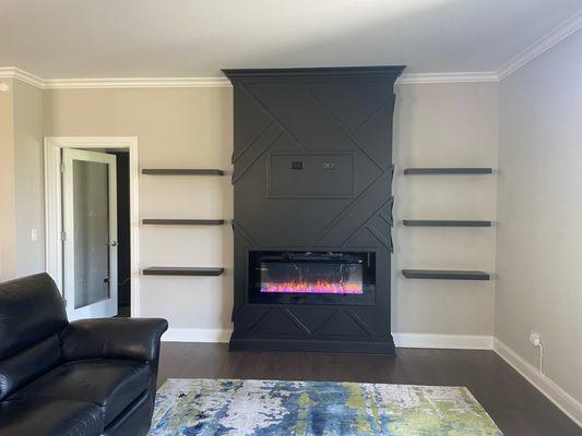 Feature wall w/floating shelves and electric fireplace.