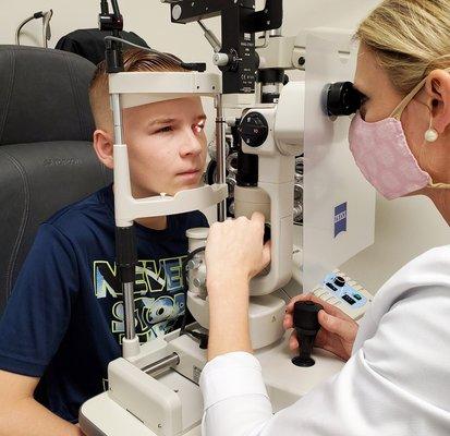 Doctor performing an eye exam on a young boy at True Eye Experts Fort Myers.