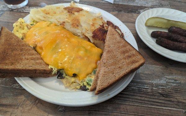 Omelet with cheese oddly "melted" on top, side of burnt sausage