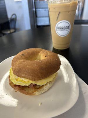 Onion Bagel Breakfast Sandwich with bacon, egg, and Gouda cheese; large Iced Latte with sugar free caramel and oat milk.