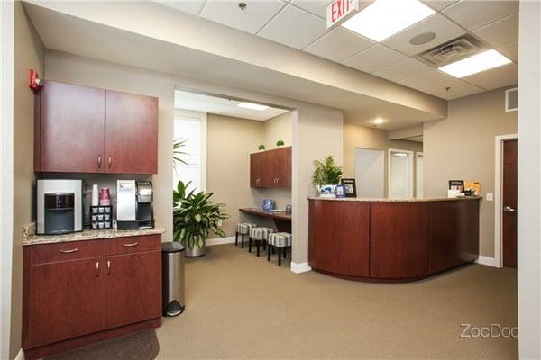 Amenity-filled waiting room with beverage station, huge flat-screen tv and iPad counter.