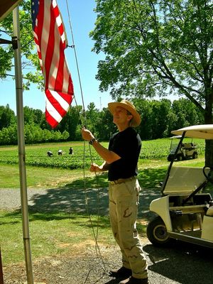 Pictured is Bob's son Jon, a Navy veteran, raising the flag in the early morning with strawberries being picked in the background.