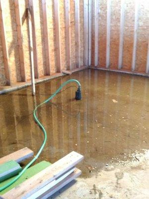 Pumping the water. Arm N Hammer claimed the concrete was poured to run out the front of the garage. This is the back corner.