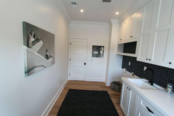 Laundry room, custom cabinets, quartz countertops, hardwood floors and black pillow ceramic mosaics