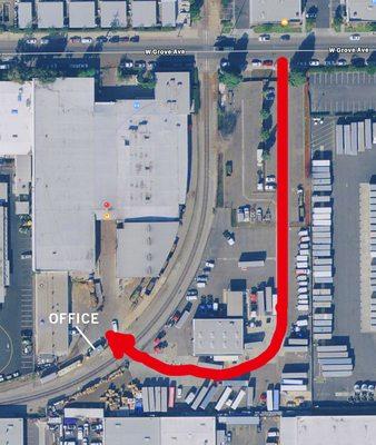 Enter thru the parking lot to the left of the building, driving all the way to the back, past the large shipping trucks, then to the right.