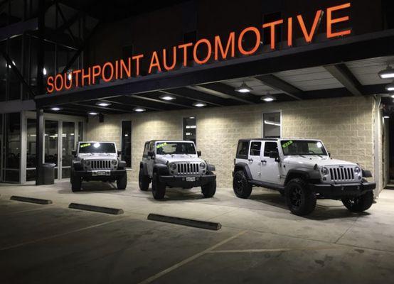 The illuminated sign of Southpoint Automotive shines brightly against the dark sky, highlighting rugged jeeps ready for adventure.