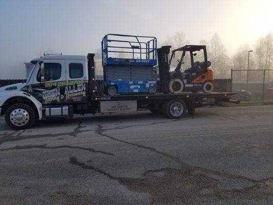 Tow truck carrying construction equipment