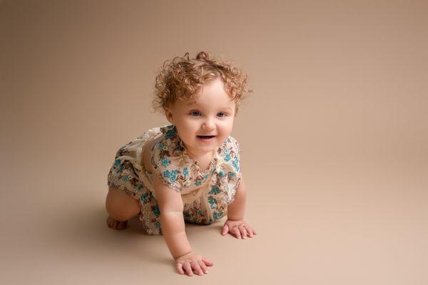 baby girl smiling and crawling towards the camera during her cake smash session