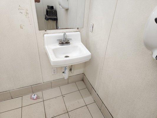 Soap dispenser on floor. Look how dirty the walls and floor are.