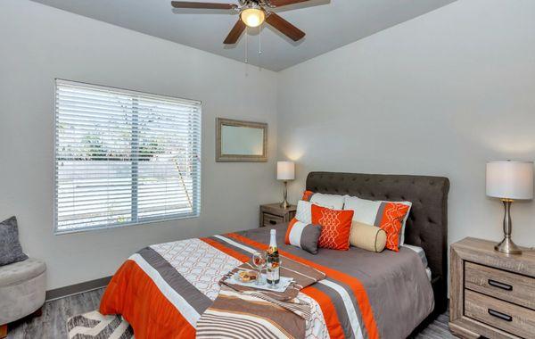 Cozy Bedroom with Brightly Colored Bedding, a Ceiling Fan, and Plank Flooring