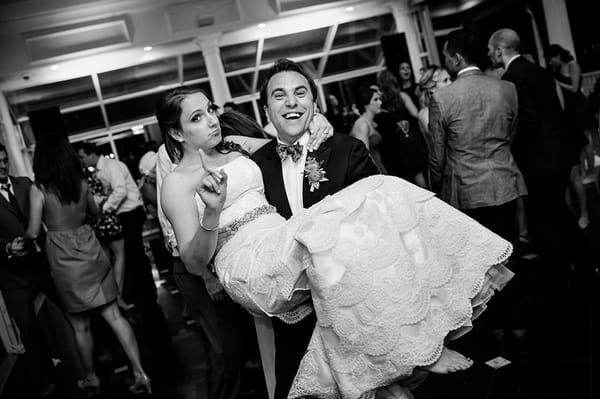 Bride carries groom at the end of wedding reception.