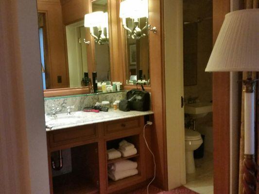 Bathroom and vanity in traditional double room. Lots of counter space, mirrors and lighting.