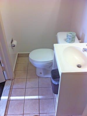 tiny bathroom which requires a person to sit on the toilet sideways due to lack of leg room