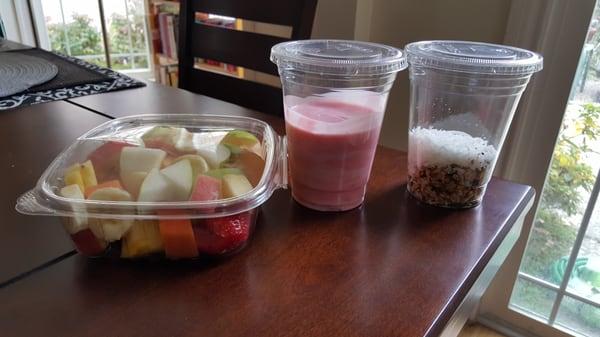 A wide variety of fresh fruit with a side of sweet cream and yogurt mixed and a side of coconut and granola mixed.