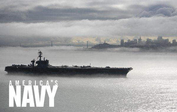 An aircraft carrier sits in the bay during fleet week.