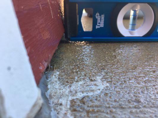 Concrete slopes towards the garage, and water runs inside under seal plate.