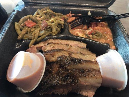 Sliced brisket with two sides - green beans and beans. Spicy BBQ sauce on the side.