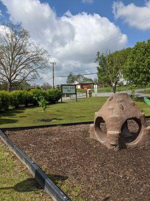 Park sign near parking area that's accessible to the picnic shelter, play ground, and lower nature inspired play area.