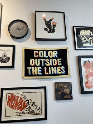 Gallery wall of art, "Color outside the lines" featured prominently.