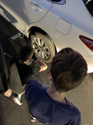 Teaching young men how to change a tire. Life skills.