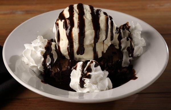 Warm brownie topped with whipped cream, ice cream, and chocolate syrup.