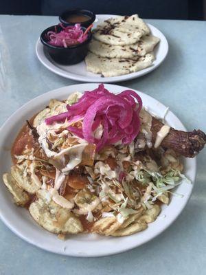 Fried chicken platter. It has fried plantains on the bottom and a cabbage salad above with pickled onions