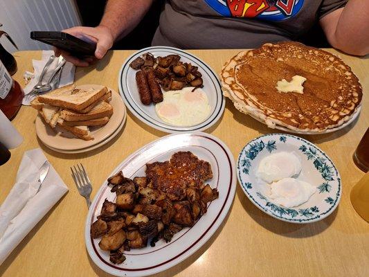 Home fries with onions & peppers, hot sausage patty, poached eggs, a huge pancake, two over easy eggs, breakfast sausage links.