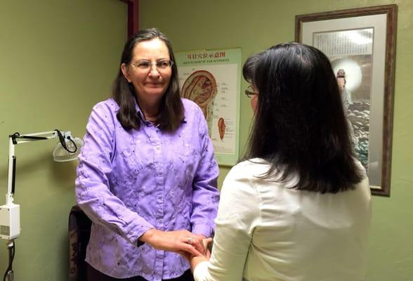 Joyce is "taking pulses" of a client.  Reading pulses is one the ways an Oriental Medicine Practioner accesses the health of ...