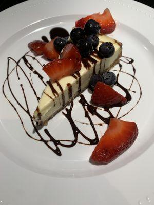 Cheesecake with fresh berries and chocolate drizzle.