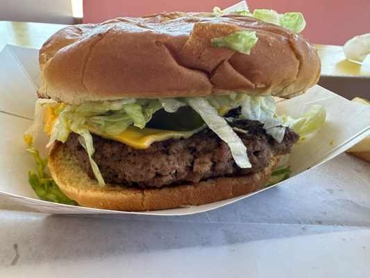 Cheeseburger with lettuce, mayonnaise, mustard and pickles.