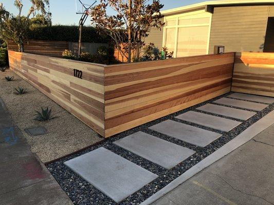 Redwood clear fence along with concrete steps and Mexican beach pebble. Talk about curb appeal