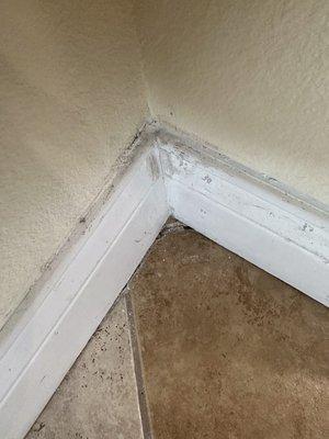 Cracked tile in corner and bad caulking on baseboards