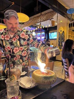 Bartender sprinkling cinnamon onto the "volcano" of our Flaming Puka Puka drink.