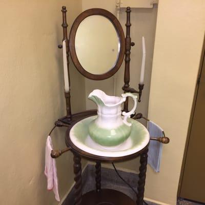 Old lavatory washstand.  Note the basin with matching pitcher, candles by the mirror, and towel racks with pink and blue hand towels!