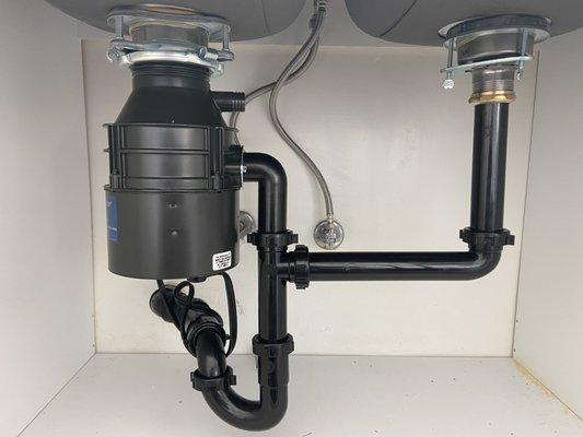 Replacement of a garbage disposal and waste pipes underneath a kitchen sink.