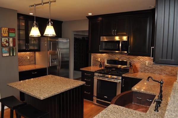 Maple cabinetry with black finish, granite counters and a copper farm sink.