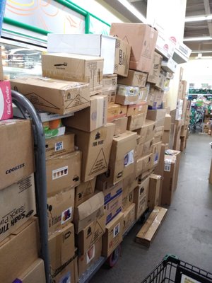 These boxes are in the middle of the aisle in front of the frozen food freezers. some boxes  are even tilting over.