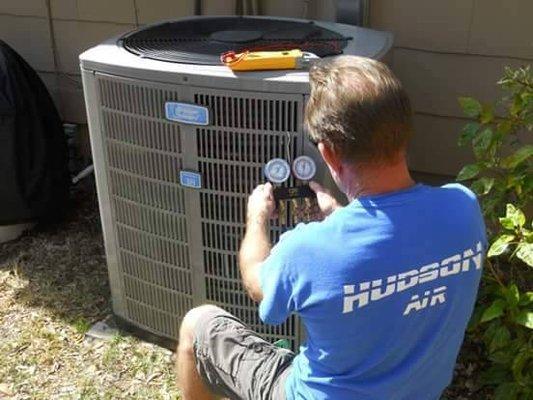 Hudson Air LLC service tech performing an expert diagnostic on an A/C unit. Professional HVAC repair and maintenance.