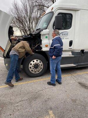 Instructor training student on vehicle front end maintenance.