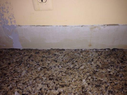 No backsplash- bashed in my wall to make the counter fit, and left it like this!