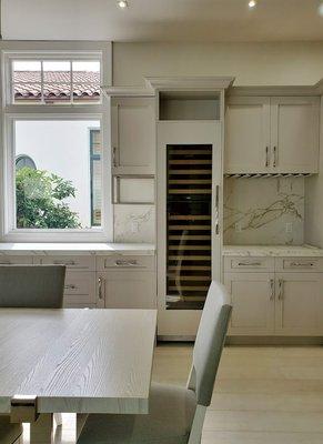 Soft gray kitchen with integrated appliances and metal shelves.