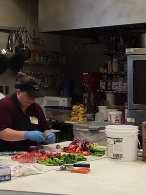 Prepping food. The kitchens are in the open.  Look at all the fresh veggies!