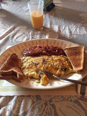 A mushroom, provolone omelette with a side of corned beef has accompanied by some whole wheat toast. Glass of oj to wash it all down.