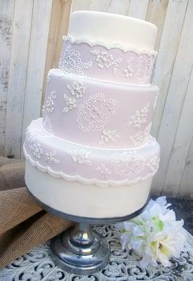 Dusty pink three tier wedding cake with hand-piped lace detail.