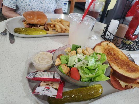 cali club melt sandwich, caesar salad, pickles, saltine crackers, lemonade, pulled pork sandwich, steak fries