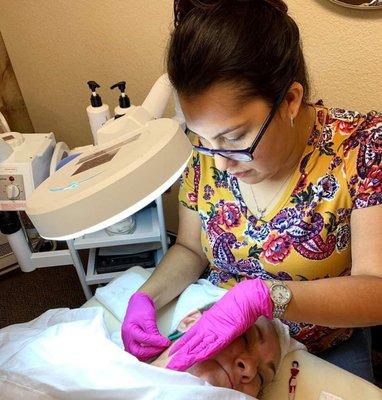 Angel  co-owner and licensed esthetician performing a dermaplane facial